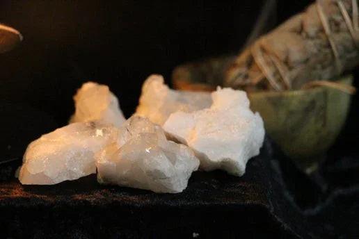Raw white crystals with sage bundle on dark altar, ritual tools for spiritual practice
